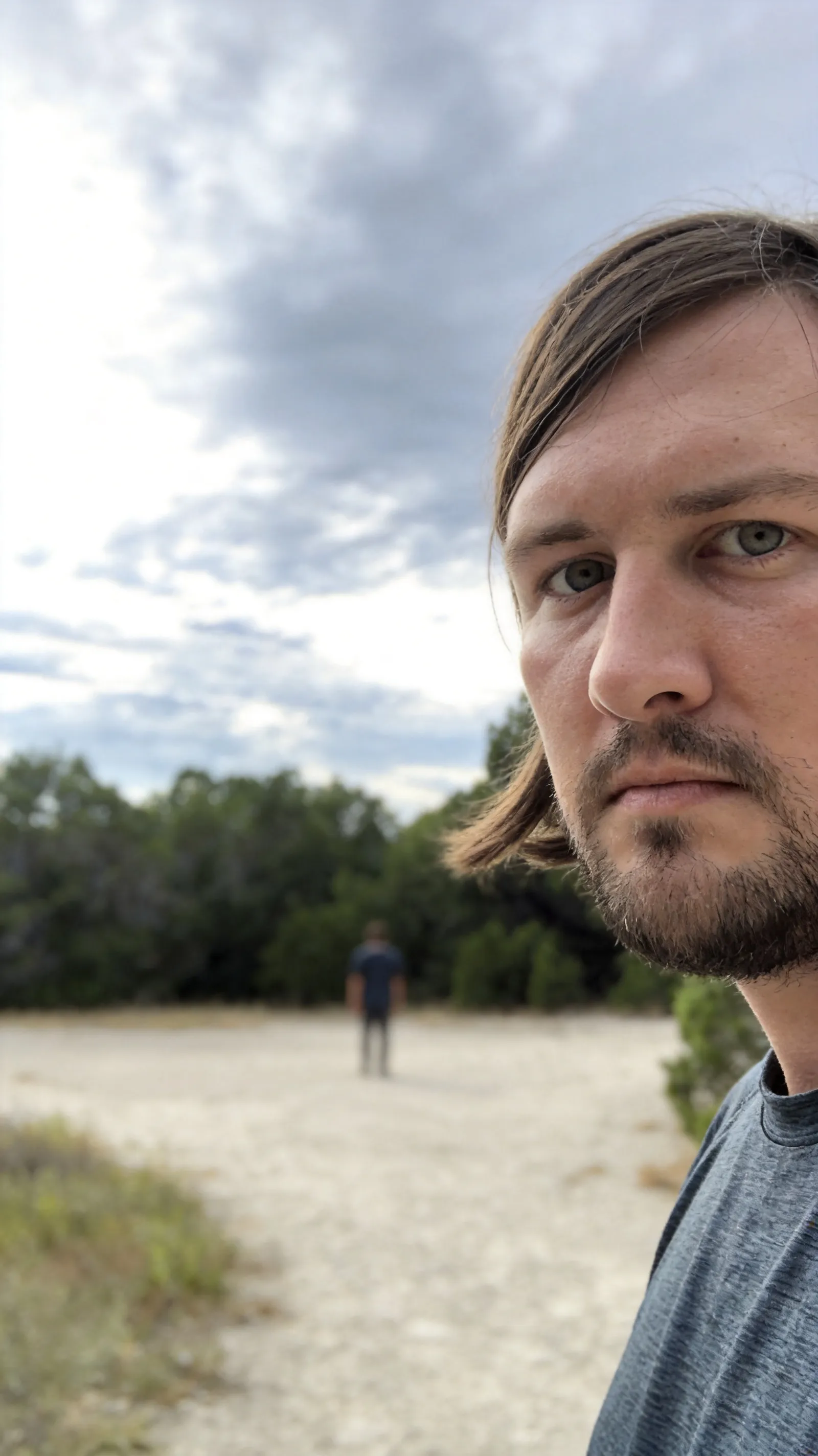Expand this image, make the image match the original one.  The person needs to be standing 200 meters far away in the distance so it's hard to see them.
