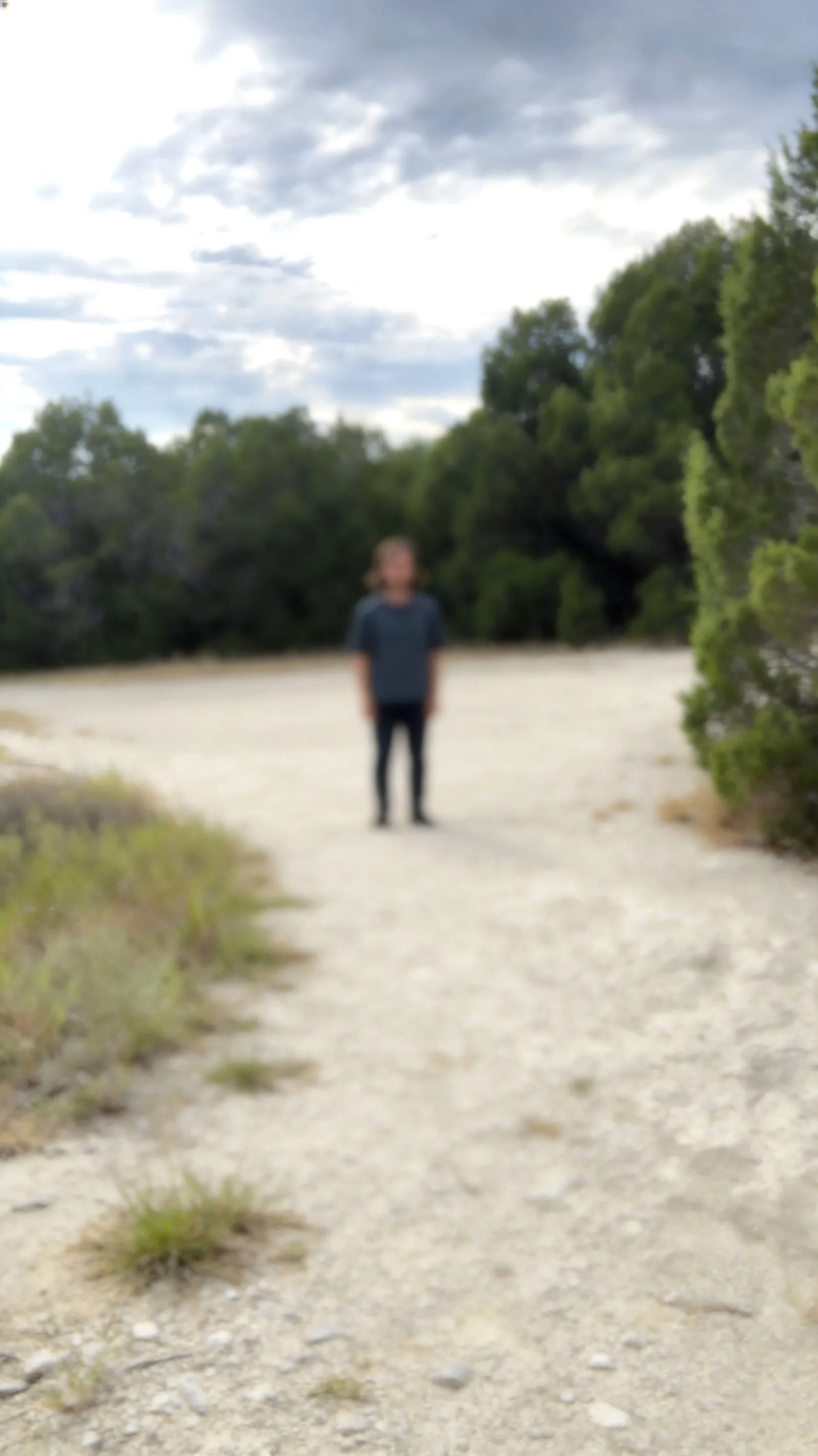 Expand this image, make the image match the original one. The person needs to be standing 200 meters far away in the distance so it's hard to see them. The person in the foreground needs to be removed. And the person in the background needs to be in focus but still far away.