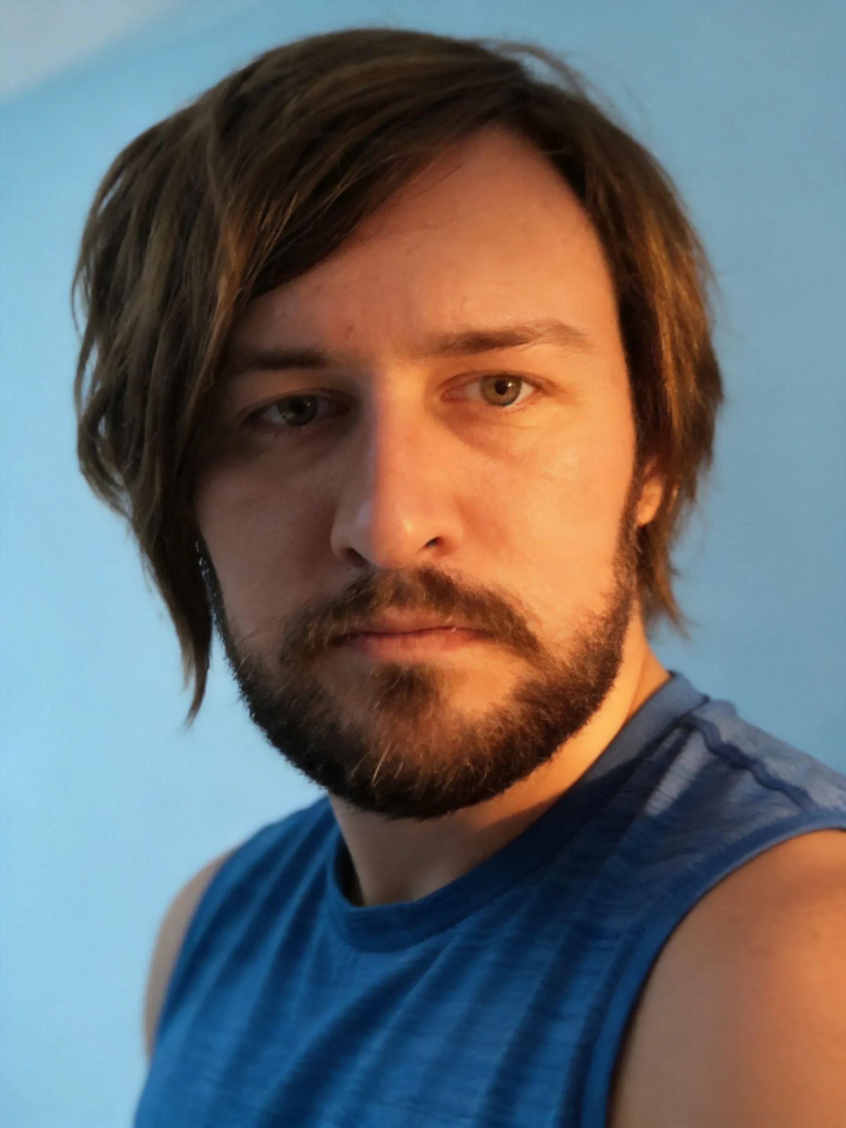 Make this the best profile picture ever. Make the lighting warm and cozy but not too extremely warm.  Make the lighting perfect. Make the angle epic and the face is in a very heroic pose. Make the wall behind him a soft baby blue. Make his eyes well lit so they are focal points on the image.