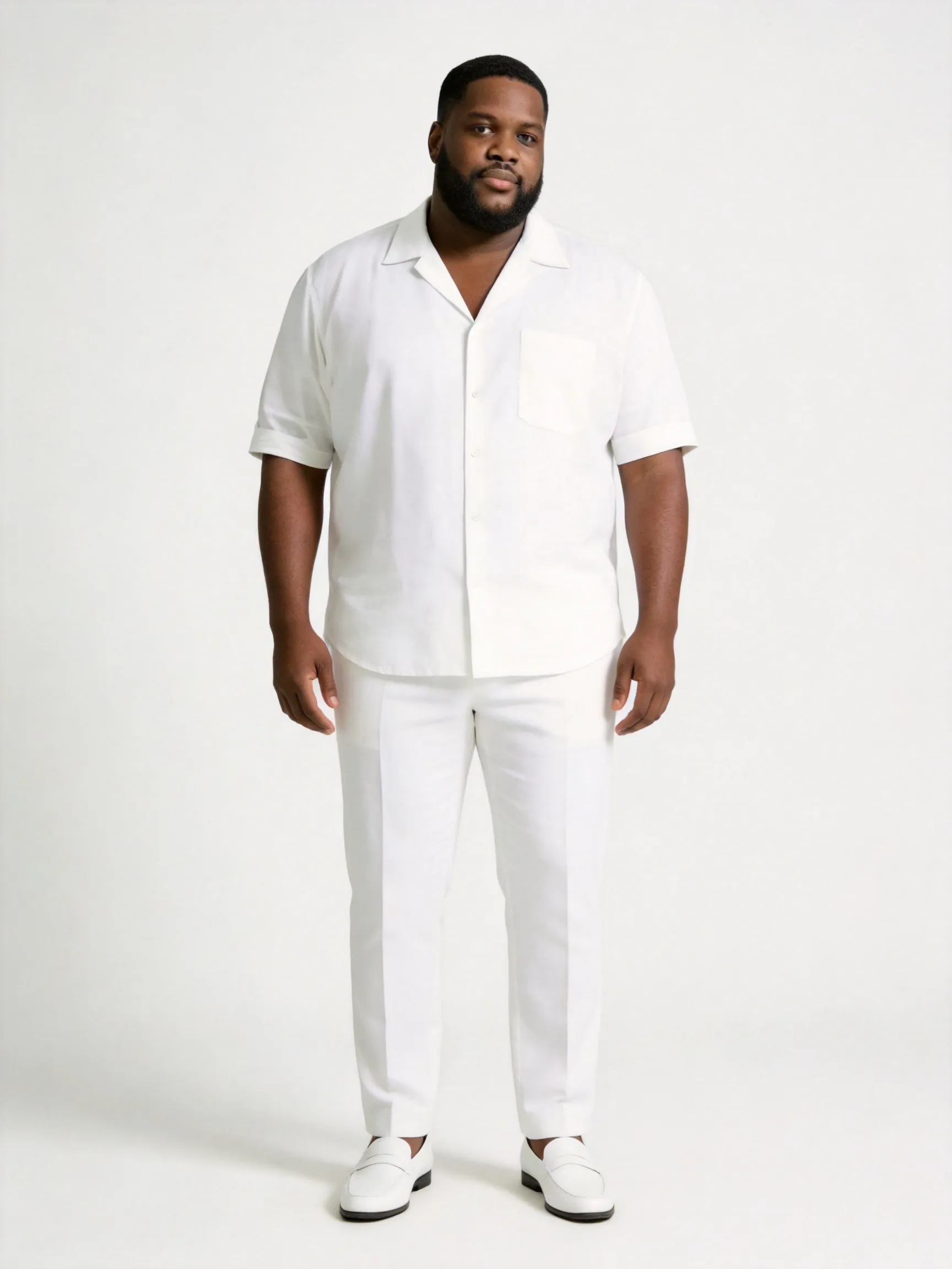 Full body shot of the man from the reference image, standing in a natural, confident and relaxed full-length posture. He features his distinctive short buzz cut hair, well-groomed beard, and calm facial features. He is wearing a sophisticated all-white monochromatic ensemble: a premium white linen short-sleeve button-up shirt with a camp collar, paired with matching well-tailored white trousers and clean white leather loafers, maintaining a luxurious, clean, and minimalist aesthetic. The background is a plain, seamless studio backdrop in a pure, soft off-white hue with gentle diffused lighting, keeping the environment and bright color tone completely consistent with the reference image. High-end fashion editorial photography style, sharp focus, 8k resolution, photorealistic --ar 3:4 --v 6.0