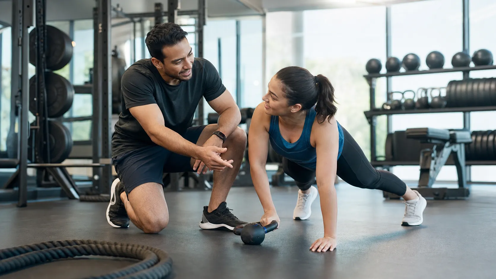 A realistic commercial photo of a personal trainer coaching an adult client in a modern gym, natural candid moment, supportive professional atmosphere, clean fitness equipment, diverse adults, suitable for a fitness coaching advertisement or landing page, no text, no logo Negative prompt: unrealistic muscles, awkward pose, distorted body, blurry, low quality, overposed stock photo, text, watermark, logo