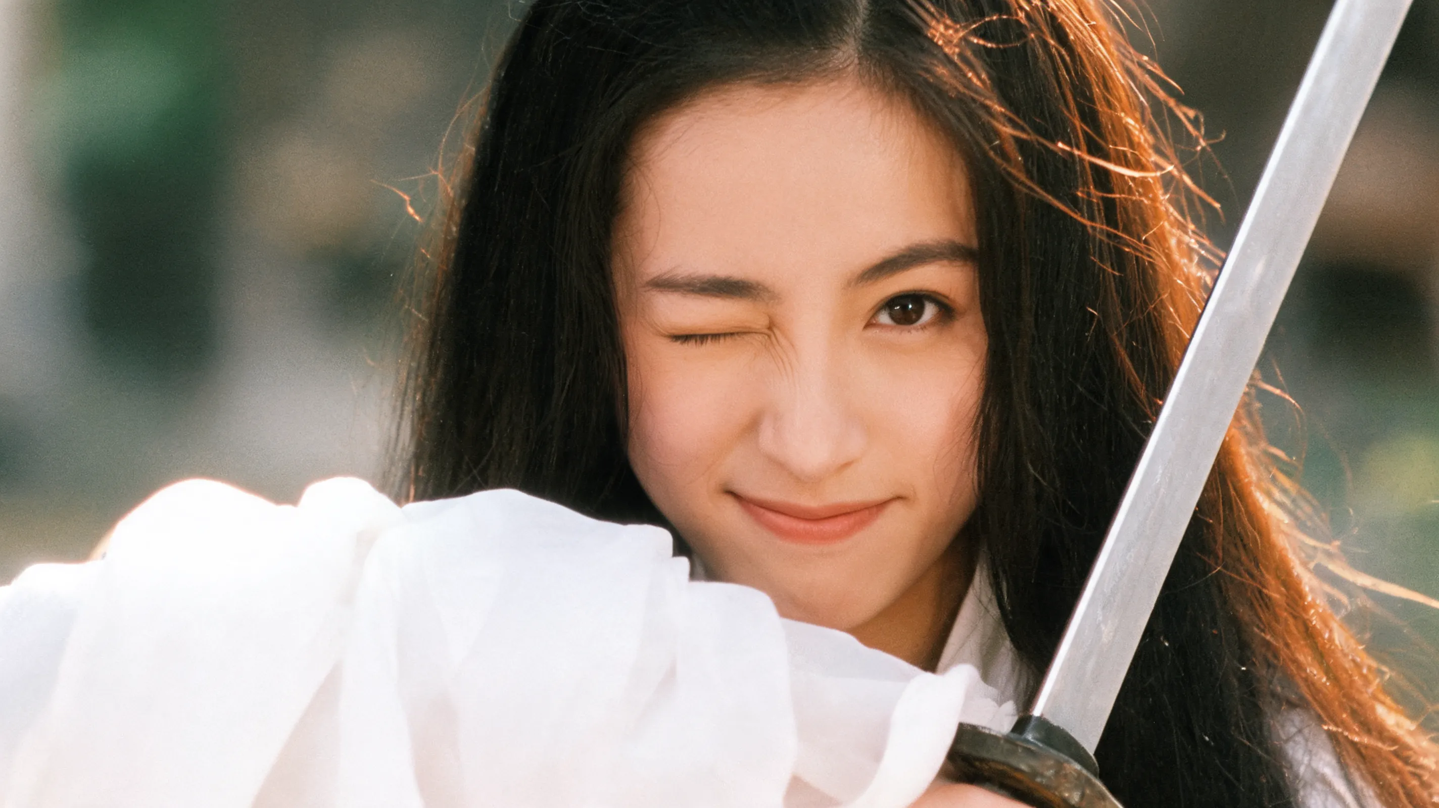 Cinematic close-up portrait of Lin Zixia (inspired by Athena Chu), wearing traditional white ancient Chinese costume with flowing sleeves, delicate features, long black hair, winking playfully with a mischievous smile, holding a sword, warm golden hour lighting, shallow depth of field, nostalgic 1990s Hong Kong film aesthetic, nostalgic film grain, highly detailed facial expression, 8k resolution.