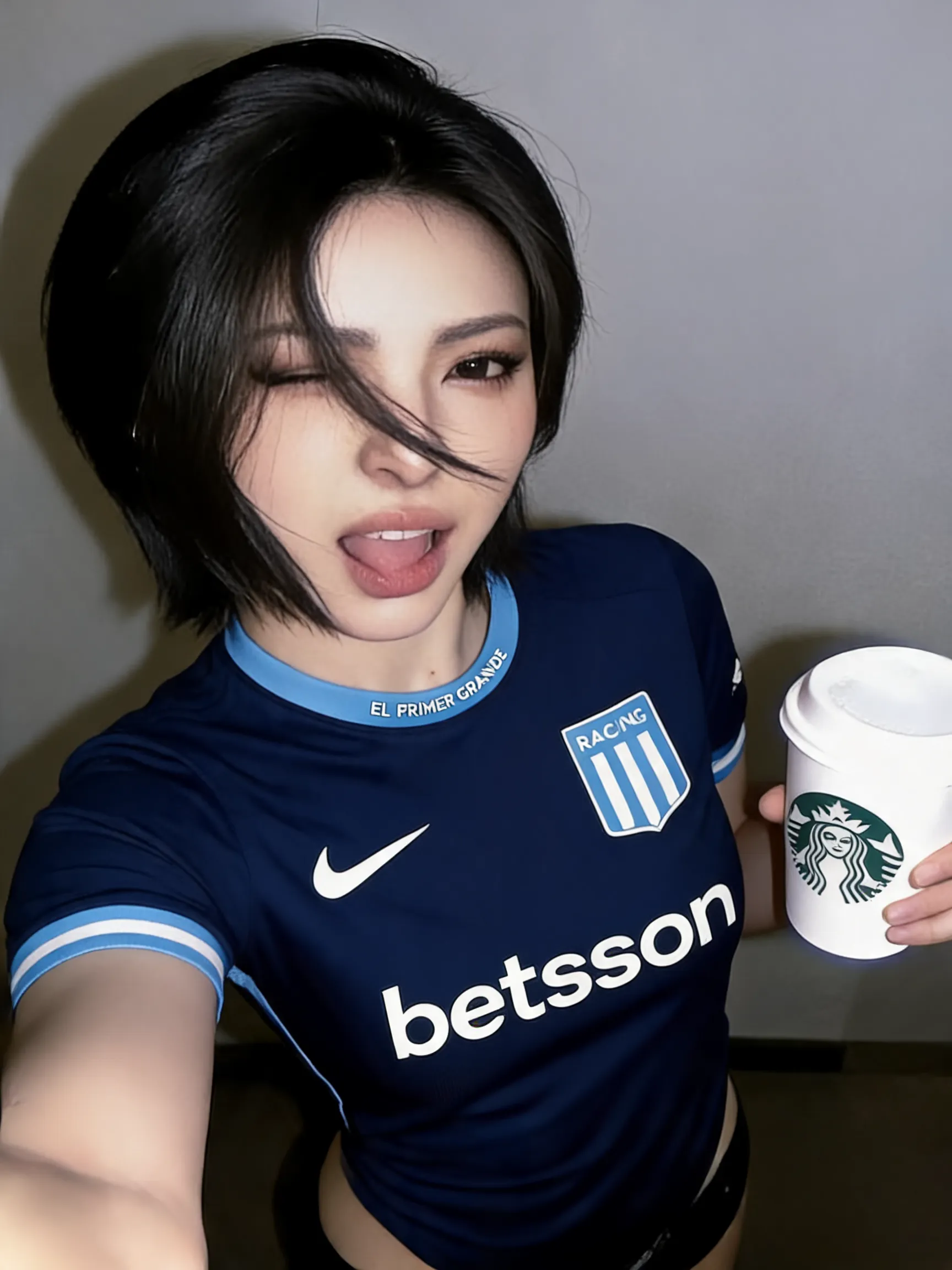 Replace only the shirt with the provided football jersey. Keep the person’s identity, facial features, hair, body proportions, skin, hands, pose, background, camera angle, lighting, shadows, and overall composition unchanged. Improve the image quality and facial clarity while preserving the person’s original appearance. Make the face sharper, more detailed and natural, with realistic skin texture and balanced lighting. Enhance the overall photographic quality, resolution, focus and realism without changing the person’s identity or body. Make the new football jersey look completely natural and realistically worn, with accurate proportions, fabric texture, stitching, folds, shadows and fit. Do not alter anything else in the image. Preserve the original composition and pose as closely as possible.