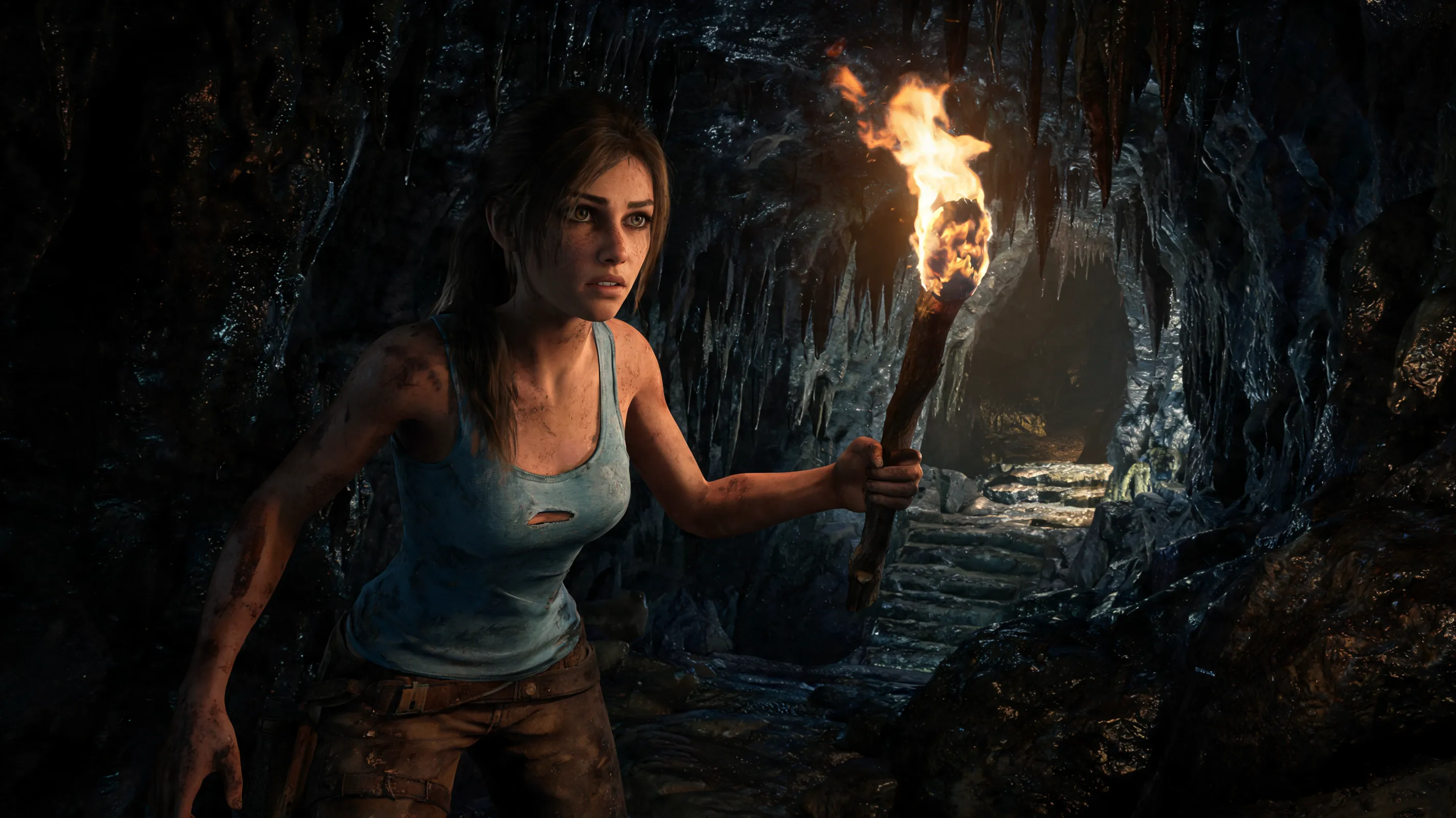 Lara Croft, wearing a torn, dirt-stained light blue tank top and brown pants, stands in a dark, damp cave, holding a lit torch; her face illuminated by the fire, eyes wide with fear and determination; survival instinct highlighting a hidden path in the environment; hyper-realistic, gritty texture, cinematic lighting, 8k, Unreal Engine 5.