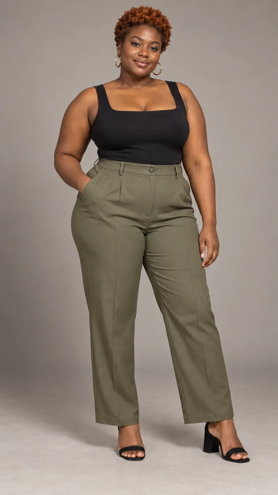 Create a photorealistic full-body fashion studio photograph of a 32-year-old Black woman, approximately 165 cm tall, with a plus-size body, naturally full arms, a rounded abdomen, broad hips, deep warm-brown skin, dark eyes, and short tightly coiled hair dyed a rich copper-auburn color. She wears a fitted black square-neck top, high-waisted muted-olive tailored trousers, gold hoop earrings, and elegant black block heels. Maintain authentic body proportions and realistic garment fit, especially around the waist, hips, and upper arms. Her pose is confident and comfortable, with a subtle smile and relaxed hands. Soft studio lighting, clean warm-gray background, detailed skin texture, individual coils, realistic trouser creases, premium inclusive fashion photography, full head-to-toe framing, both shoes visible, vertical 9:16. No text, no watermark, no slimming distortion.